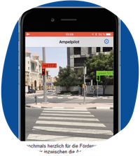 Screenshot der App Ampelpilot. Gezeigt wird eine Straßenkreuzung mit zwei Ampeln. Die Ampeln sind in der Farbe markiert, in der sie leuchten und entsprechend mit 