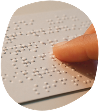 Ein Zeigefinger tastet die Oberfläche einer Braille-Schrift auf einem Papier ab